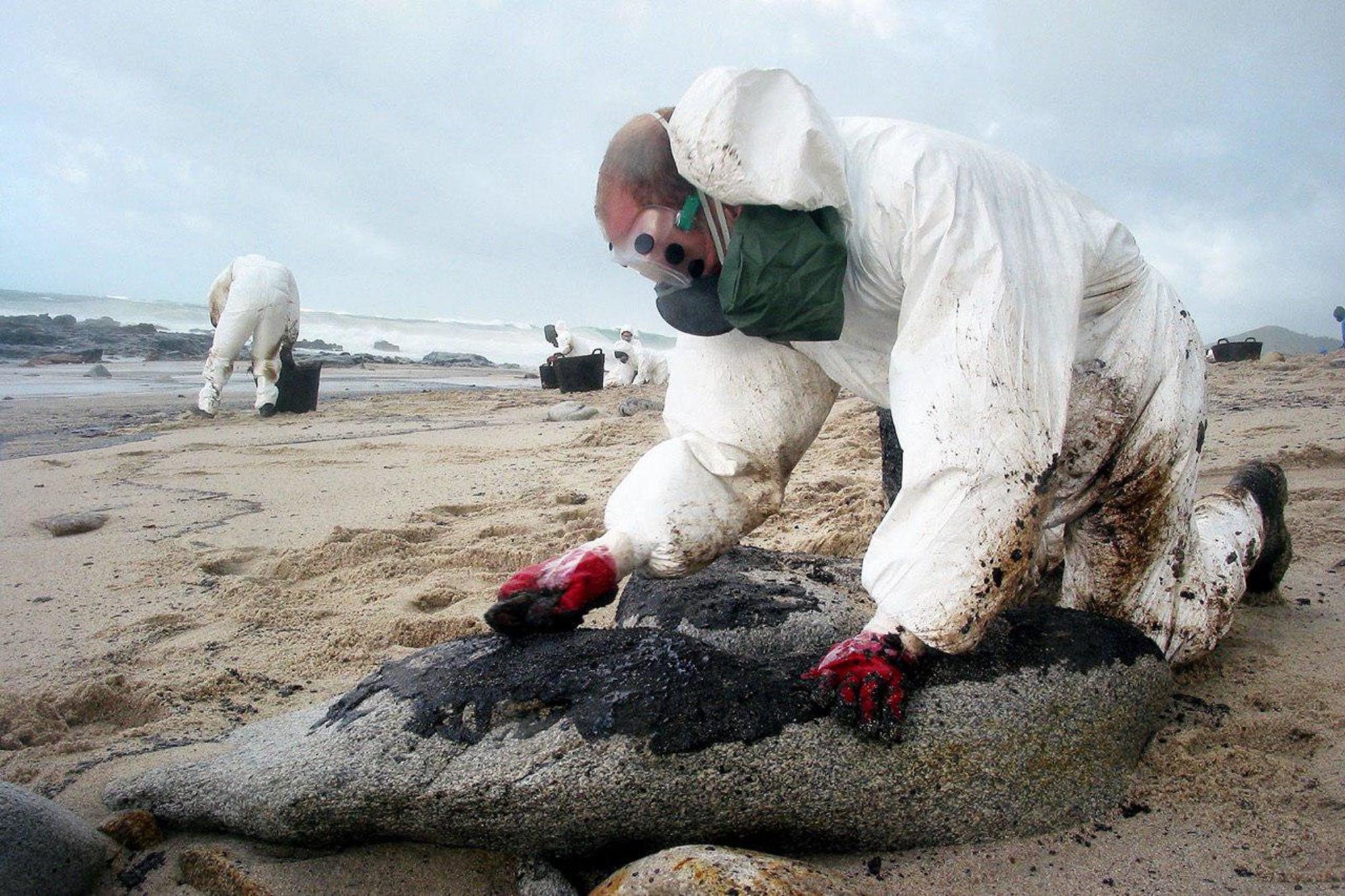 Voluntarios limpian chapapote en la costa gallega procedente del Prestige